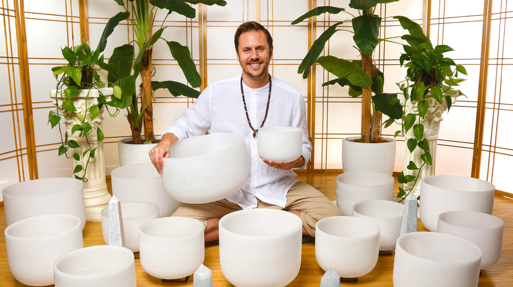 Travis surrounded by chakra singing bowls