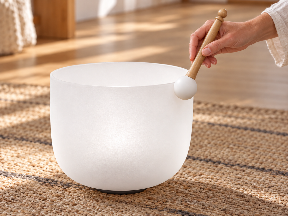 A hand playing a crystal singing bowl with a mallet at home