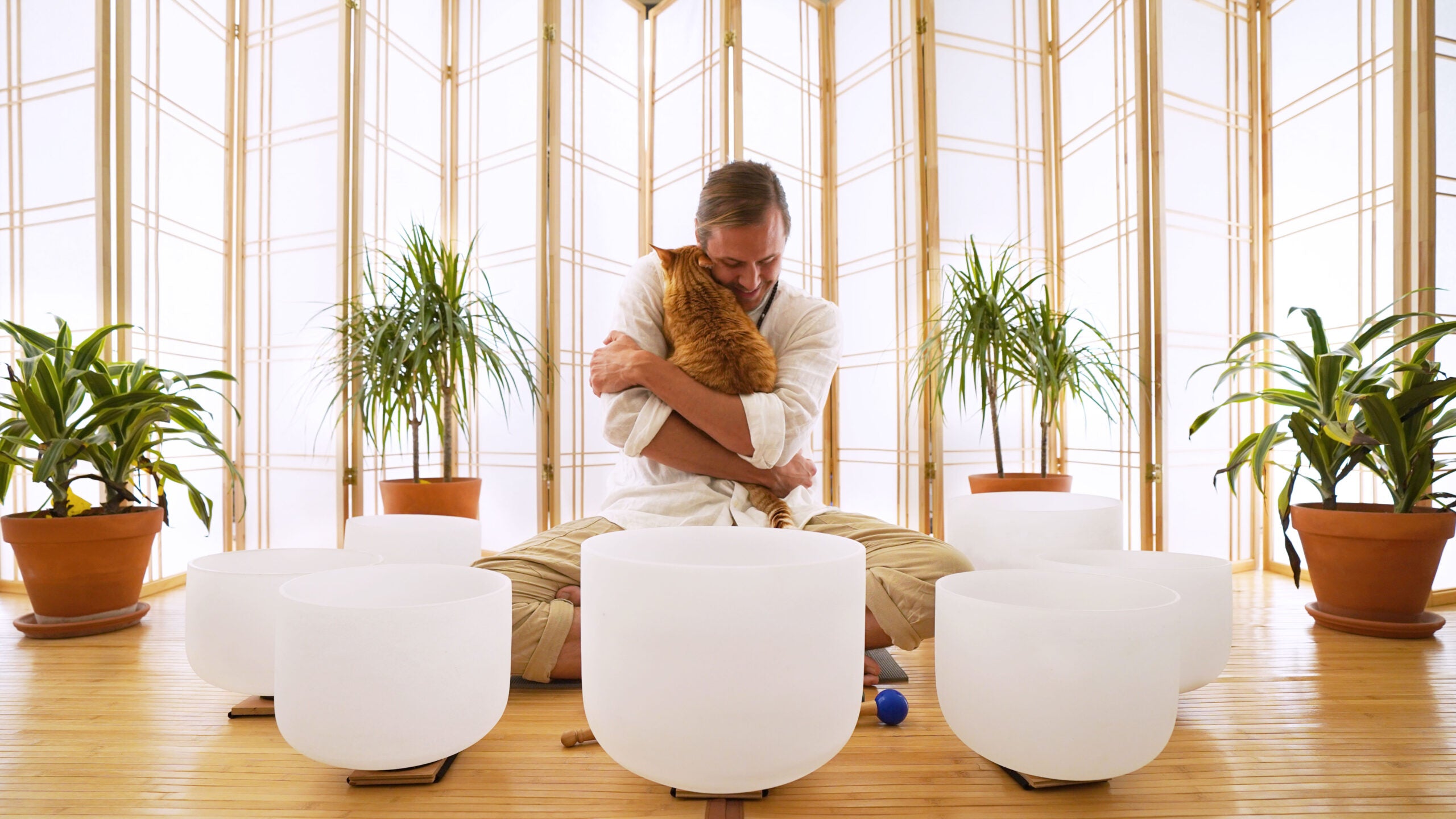 Travis Schumacher sitting with cat and crystal singing bowls